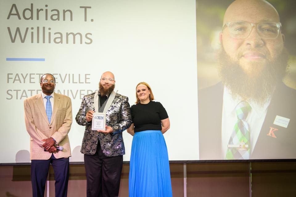 Adrian T. Williams, center, receives an award from Myron Pitts and Beth Hutson at the Fayetteville Observer's 40 Under 40 award ceremony at Fayetteville State University on Tuesday, July 18, 2023.