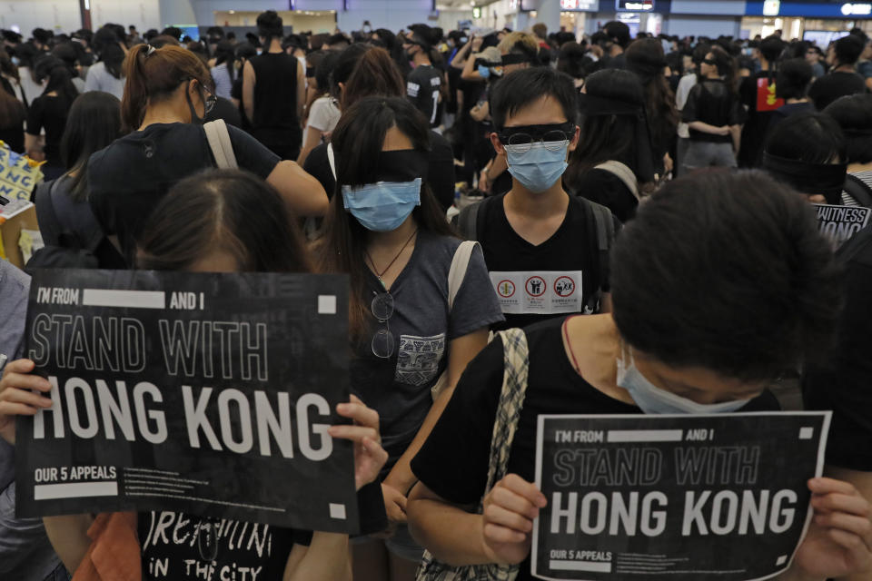 Protesters wear blind folds and hold placards as thousands take part in a second day of sit-in protest at the airpot in Hong Kong on Saturday, Aug. 10, 2019. Hong Kong is in its ninth week of demonstrations that began in response to a proposed extradition law but have expanded to include other grievances and demands for more democratic freedoms. (AP Photo/Kin Cheung)