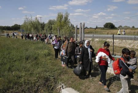 Migrants walk along a road protection fence as they leave a collection point in the village of Roszke, Hungary September 9, 2015. REUTERS/Marko Djurica