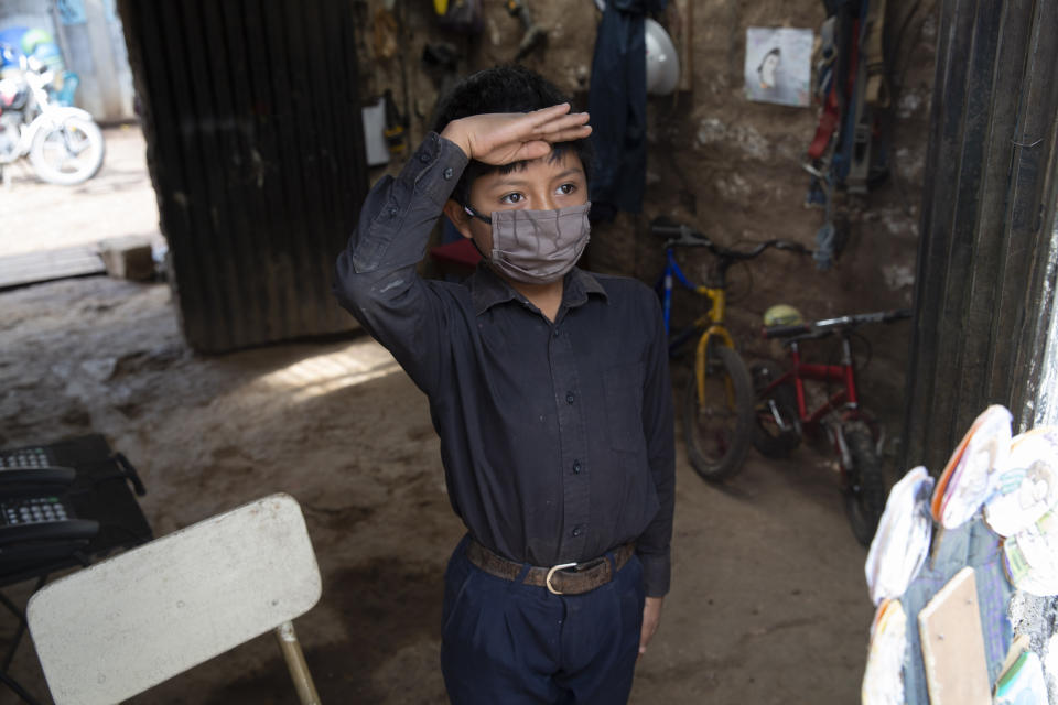 Standing just inside the doorway of his home in a black button down shirt tucked into navy blue trousers, 11-year-old Oscar Rojas greets his teacher Gerardo Ixcoy, known universally as "Lalito 10", in Santa Cruz del Quiche, Guatemala, Wednesday, July 15, 2020. "Teacher Lalito only comes for a little while to teach me, but I learn a lot." (AP Photo/Moises Castillo)