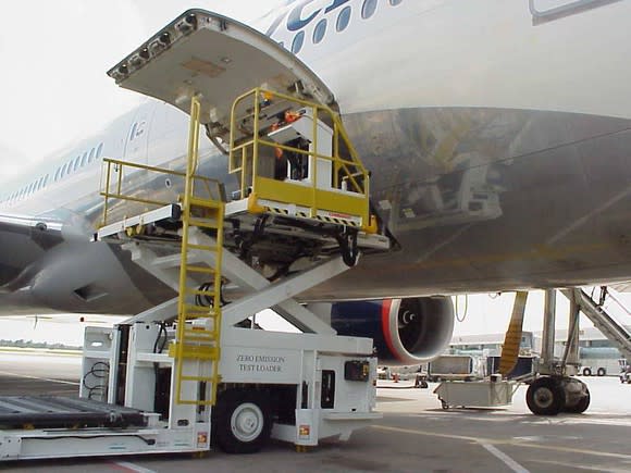 Aircraft loader with its platform raised to the cargo level of a jumbo jet.