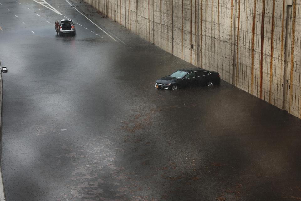 A highway flooded with water. A car is stuck.