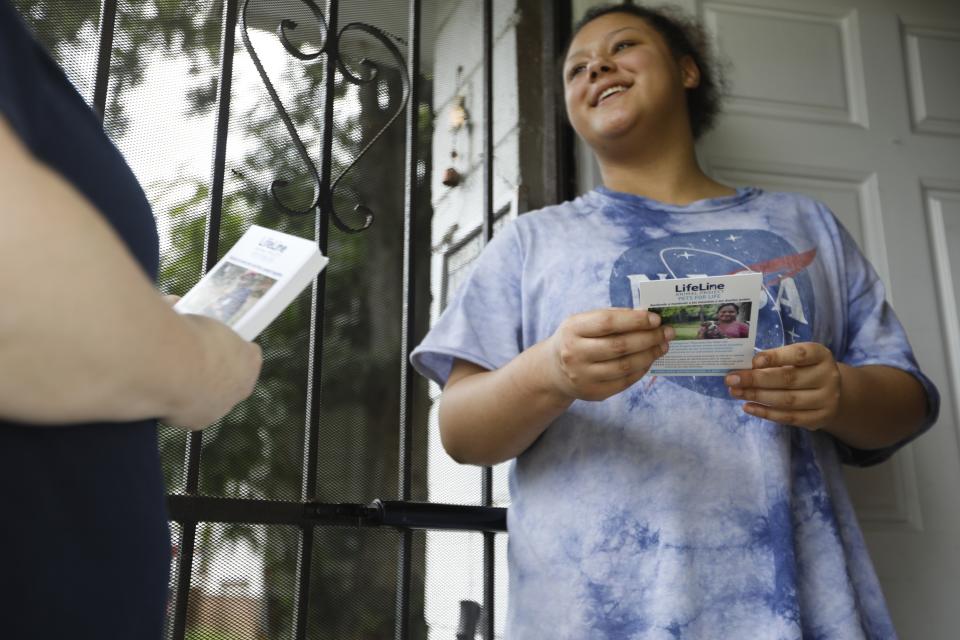 In this Tuesday, Aug. 27, 2019 photo, Shayla Finley opens her door to hear Lizzy Trawick explain LifeLine Animal Project's Pets for Life program in Atlanta. The program provides free resources, such as food and vaccinations, to pet owners in need. "I'm so glad you guys are doing this," Finley said. (AP Photo/Andrea Smith)