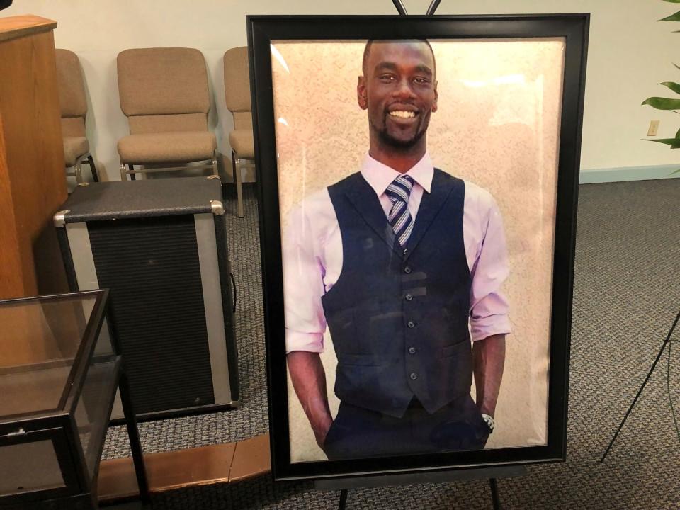 A portrait of Tyre Nichols, a Black man wearing a suit, in a black frame