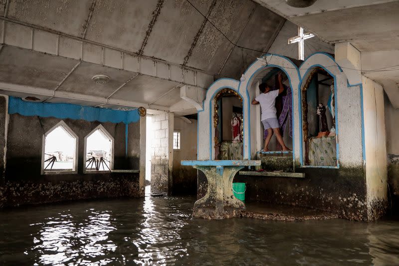 The Wider Image: Rising seas threaten early end for sinking village in Philippines