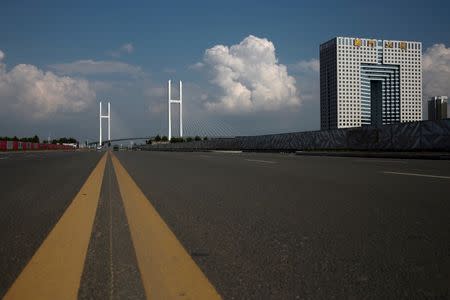 An empty street runs in front of the unfinished New Yalu River bridge (L) and the empty Chinese customs building in Dandong, Liaoning province, China, September 11, 2016. The bridge was designed connect China's Dandong New Zone and North Korea's Sinuiju. REUTERS/Thomas Peter