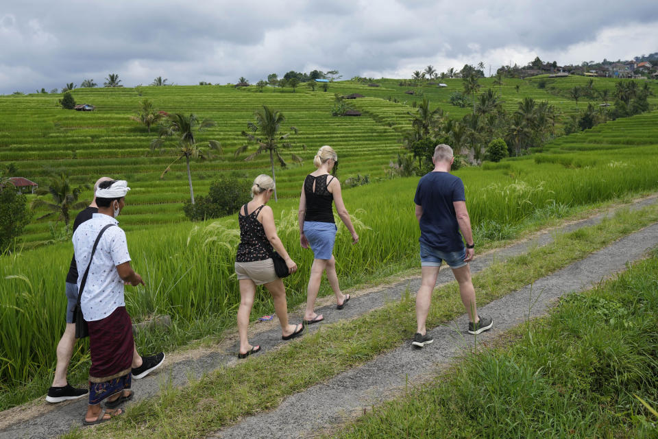 Tourists walk near rice fields irrigated by a traditional terrace system called a "subak" in Jatiluwih in Tabanan, Bali, Indonesia, Monday, April 18, 2022. Bali faces a looming water crisis from tourism development, population growth and water mismanagement, experts and environmental groups warn. While water shortages are already affecting the UNESCO site, wells, food production and Balinese culture, experts project these issues will worsen if existing policies are not equally enforced across the entire island. (AP Photo/Tatan Syuflana)