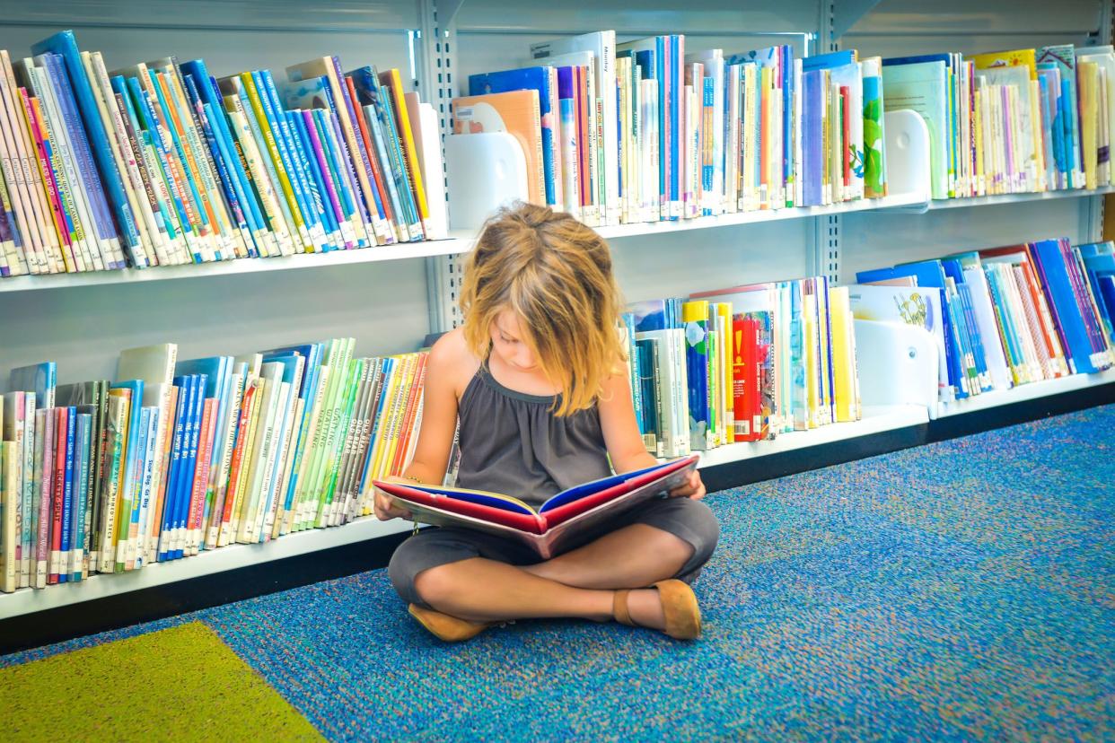 elementary school student sitting on floor reading