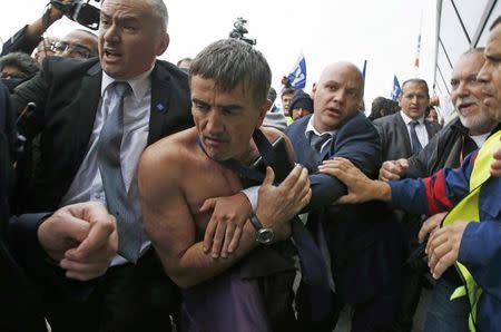 A shirtless Xavier Broseta (2ndL), Executive Vice President for Human Resources and Labour Relations at Air France, is evacuated by security after employees interrupted a meeting with representatives staff at the Air France headquarters building at the Charles de Gaulle International Airport in Roissy, near Paris, France, October 5, 2015. REUTERS/Jacky Naegelen