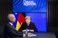 German Klaus Schwab, left, Founder and Executive Chairman of the World Economic Forum, WEF, listens to German Chancellor Angela Merkel, displayed on a video screen, during a conference at the Davos Agenda in Cologny near Geneva, Switzerland, Tuesday, Jan. 26, 2021. The Davos Agenda from Jan. 25 to Jan. 29, 2021 is an online edition due to the coronavirus disease (COVID-19) outbreak. (Salvatore Di Nolfi/Keystone via AP)