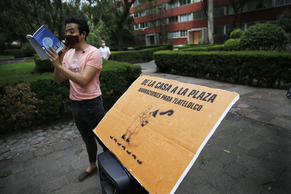 Percibald Garcia uses a microphone to read aloud children's stories amid the high-rise housing complex of Tlatelolco, in Mexico City, Saturday, July 18, 2020. Confinement during the coronavirus pandemic has been especially tedious for children, so the young architect sets out every afternoon with a microphone and a loudspeaker to walk the neighborhood where he lives and provide entertainment. (AP Photo/Marco Ugarte)