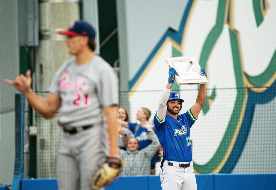 Brian Ellis, an outfielder for the Florida Gulf Coast University baseball team holds up first base in celebration after earning a walk during a game against FAU at FGCU on Tuesday, April 11, 2023. He broke the NCAA record for most consecutive times for reaching base at 102 games.