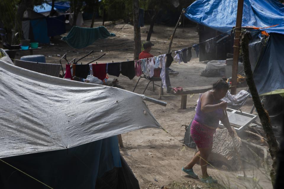 A migrant sweeps the ground at a shelter encampment in the border town of Matamoros, Mexico, Wednesday, Aug. 16, 2023. Mexico’s immigration agency and a Catholic aid group have opened a temporary outdoor shelter for migrants living in camps to move to, as Mexico’s National Institute for Migration wants this large camp in Matamoros dismantled. (AP Photo/Jacky Muniello)