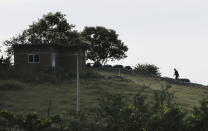 In this Oct. 3, 2019 photo, a heavily-armed vigilante is silhouetted against the horizon at a sniper post atop a hill against incursions by the Jalisco cartel, on the outskirts of Tepalcatepec, Michoacan state, Mexico. The region's avocado boom, fueled by soaring U.S. consumption, has drawn parts of western Mexico out of poverty in just 10 years. But the scent of money has drawn gangs and hyper-violent cartels. (AP Photo/Marco Ugarte)
