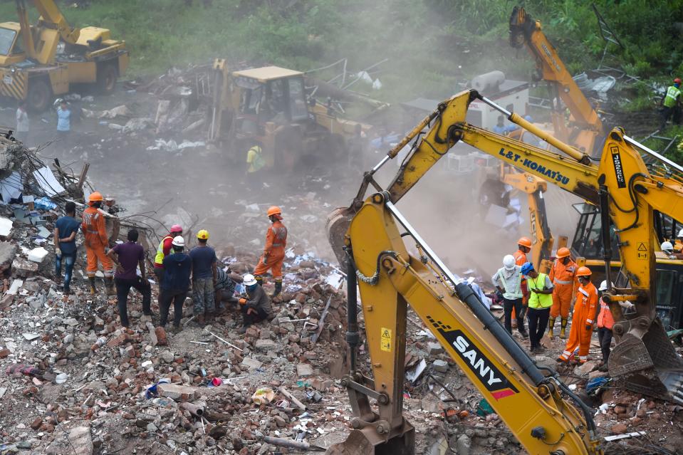 Rescue workers search for people in the rubble of a five-storey apartment building after it collapsed in Mahad. (Photo by PUNIT PARANJPE/AFP via Getty Images)