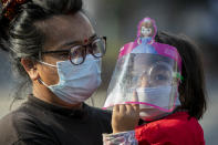 A Nepalese woman and her daughter wearing face masks as a precaution against the coronavirus watch devotees pull a chariot during the Rato Machindranath chariot festival in Lalitpur, Nepal, Saturday, May 15, 2021. A truncated version of a Hindu chariot festival took place in Nepal's capital on Saturday amid strict COVID-19 restrictions, following an agreement between organizers and authorities that prevented a repeat of violent confrontations between police and protesters at last year's festival. (AP Photo/Niranjan Shrestha)