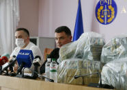 Ukraine's Anti-Corruption Prosecutor Nazar Kholodnytsky, left, and National Anti-Corruption Bureau chief Artem Sytnik at a pile of USD 6 million in plastic bags during a briefing in an anti-corruption prosecutor's office in Kyiv, Ukraine, Saturday, June 13, 2020. Ukrainian authorities say they have intercepted a USD 6 million bribe attempt at dropping a criminal investigation against the head of the Burisma natural gas company where former US Vice President Joe Biden's son once held a board seat. (AP Photo/Efrem Lukatsky)