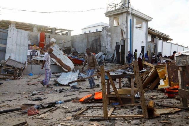 Bystanders walk through the scene of bombing at a seaside restaurant at Liido beach in Mogadishu