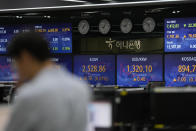A currency trader stands near the screens showing the Korea Composite Stock Price Index (KOSPI), center left, and the foreign exchange rate between U.S. dollar and South Korean won at a foreign exchange dealing room in Seoul, South Korea, Tuesday, April 11, 2023. Stocks were mostly higher in Asia on Tuesday after a mixed session on Wall Street dominated by speculation the Federal Reserve may tap the brakes again on financial markets and the economy by raising interest rates. (AP Photo/Lee Jin-man)