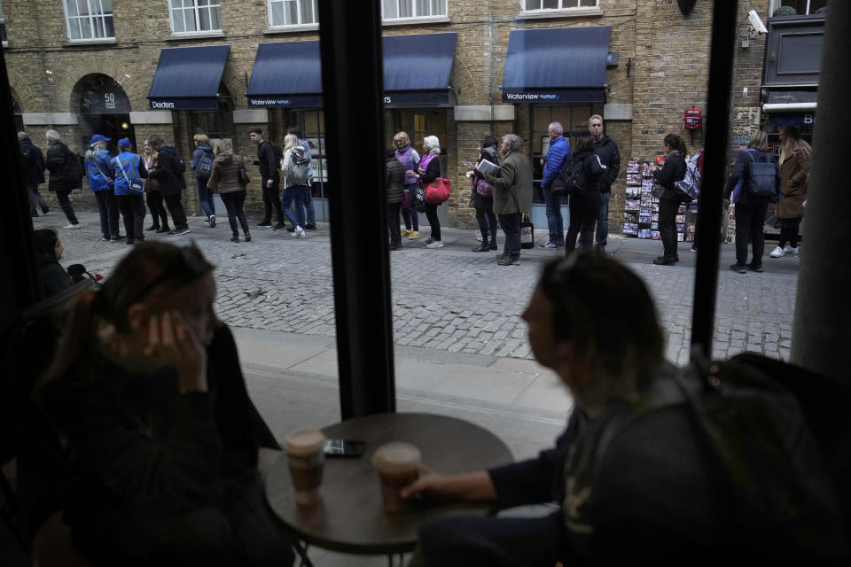 FILE - Women drink a coffee in a bar as people queue outside to pay respect to late Queen Elizabeth II, lying in state at Westminster Hall in London, Friday, Sept. 16, 2022. Hotels, restaurants and shops are packed as royal fans pour into the heart of London to experience the flag-lined roads, pomp-filled processions and brave a mileslong line for the once-in-a-lifetime chance to bid adieu to Queen Elizabeth II. (AP Photo/Christophe Ena)