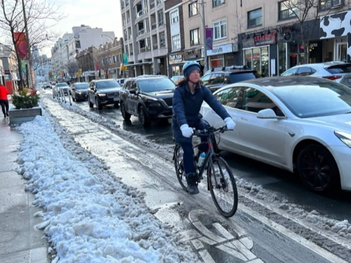 Robin Richardson, Yonge4All spokesperson and owner of an e-bike rental service, rides in the cycle track on Yonge Street at St. Clair. She says the new lanes have made her rides safer.   (Mike Smee/CBC - image credit)