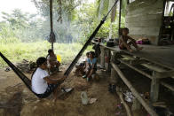 Members of the Ngabe Bugle indigenous group sit at their home in the jungle community of El Terron, Panama, Friday, Jan. 17, 2020. A pregnant woman, five of her children and a neighbor were round up by about 10 lay preachers at the hamlet on Monday and tortured, beaten, burned and hacked with machetes to make them "repent their sins", authorities said. (AP Photo/Arnulfo Franco)