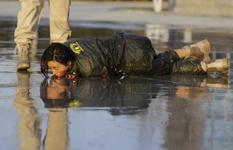 Female trainee lies on the ground after being drenched with water during Tianjiao Special Guard/Security Consultant training on the outskirts of Beijing