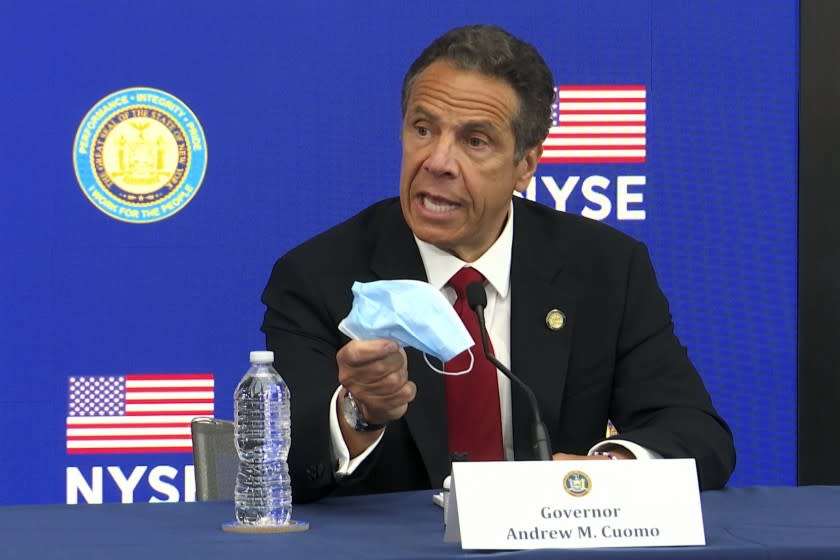 New York Gov, Andrew Cuomo holds his face mask while talking to the media at the New York Stock Exchange, Tuesday, March 26, 2020. Gov. Cuomo rang the opening bell as the trading floor partially reopened during the coronavirus pandemic. (AP Photo/Ted Shaffrey)