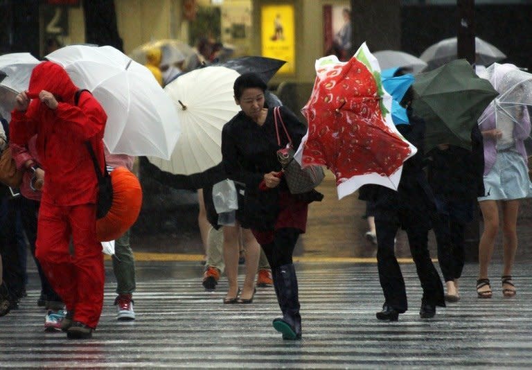 Pedestrians walk against strong wind and rain in Tokyo, on September 16, 2013