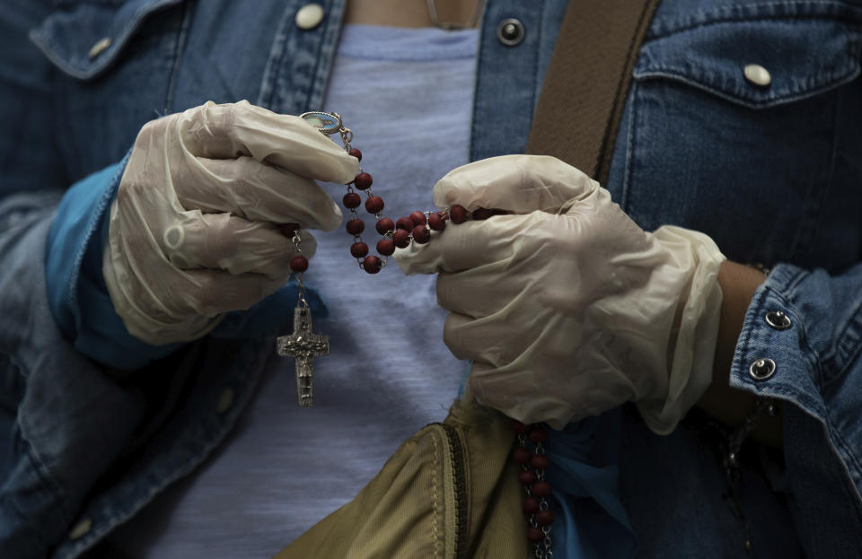 An activist against abortion wearing plastic gloves amid the COVID-19 pandemic clutches a rosary outside the Supreme Court that ruled against an injunction in Veracruz state aiming to decriminalize abortion for all cases within the first 12 weeks of pregnancy, in Mexico City, Wednesday, July 29, 2020. Two of Mexico’s 32 states have decriminalized abortion. (AP Photo/Fernando Llano)