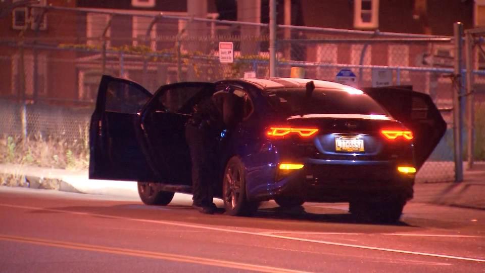 Police search a car with bullet holes early Thursday morning.