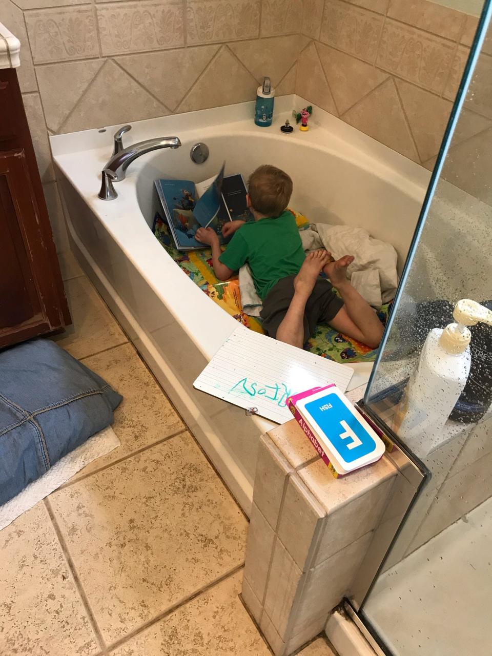 Orion Carlson, age 4, learning phonics from his makeshift classroom "tub" at home in Alameda, California.