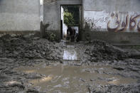 A man uses a bucket to remove water from his home after heavy rains in Charsadda, Pakistan, Tuesday, Aug. 30, 2022. Disaster officials say nearly a half million people in Pakistan are crowded into camps after losing their homes in widespread flooding caused by unprecedented monsoon rains in recent weeks. (AP Photo/Mohammad Sajjad)