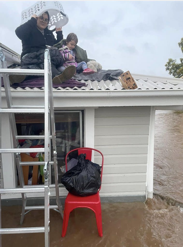 A woman and her child stranded on the roof of their house in Lismore as flood levels rise.