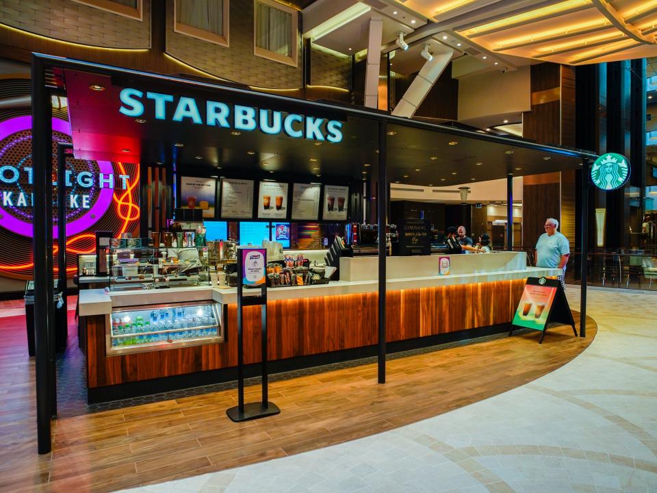 A starbucks stand on an indoor deck on a cruise ship