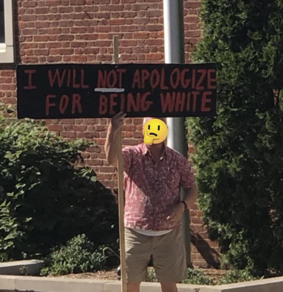 A man holding up a sign that says "I will not apologize for being white"