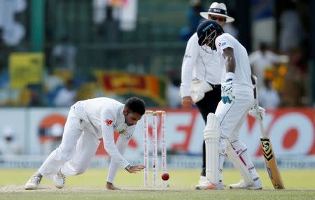 Cricket - Sri Lanka v South Africa - Second Test Match - Colombo, Sri Lanka - July 21, 2018 - South Africa's Keshav Maharaj tries to stop a ball next to Sri Lanka's Dimuth Karunaratne. REUTERS/Dinuka Liyanawatte