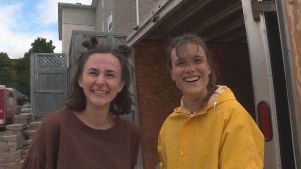 Jessica Farrer and Abby Kierstead tend to the Fosters Fresh Vegetables stall at Fredericton Boyce Farmers' Market. They say the province's shift to the green phase is welcome.  (Mrinali Anchan/CBC - image credit)