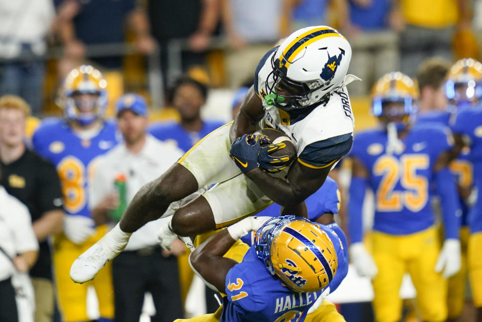 West Virginia wide receiver Bryce Ford-Wheaton makes a catch and is hit by Pittsburgh defensive back Erick Hallett (31) during the first half of an NCAA college football game Thursday, Sept. 1, 2022, in Pittsburgh. (AP Photo/Keith Srakocic)