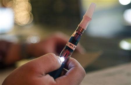 A customer holds an e-cigarette at the Henley Vaporium in New York City December 18, 2013. REUTERS/Mike Segar