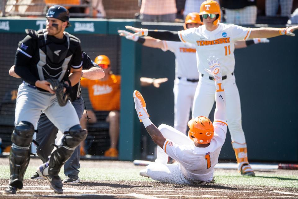 June 7: Tennessee's Christian Moore (1) and Billy Amick (11) gesture the safe sign as Moore slideds home againt Evansville in Game 1 of their super regional. Tennessee won 11-6.