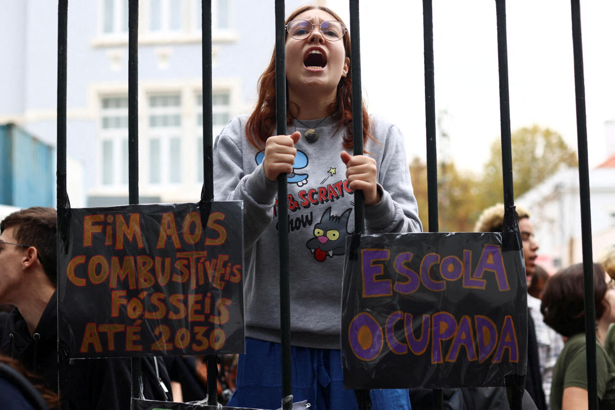 A student of Camoes school stands next to posters which read 