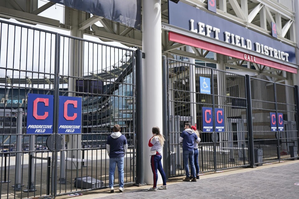 Cleveland Indians fans look into the ballpark after a baseball game between the Toronto Blue Jays and the Cleveland Indians was postponed due to inclement t weather, Saturday, May 29, 2021, in Cleveland. The game will be rescheduled as a traditional doubleheader Sunday. (AP Photo/Tony Dejak)