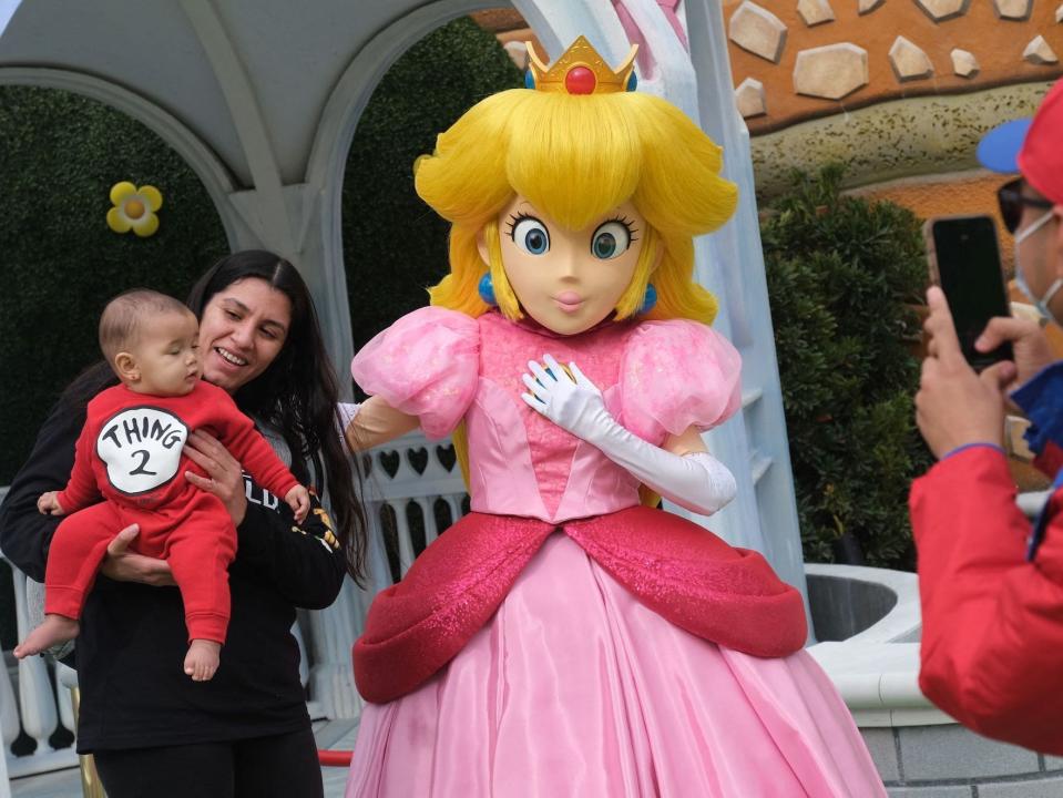 Guests take pictures with Princess Peach during a preview of Super Nintendo World at Universal Studios in Los Angeles, California, on January 13, 2023.