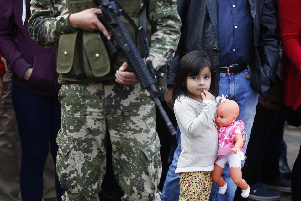 In this Aug. 15, 2018 photo, a girl holding her doll watches a military parade marking the 481th anniversary of the founding of Asuncion, Paraguay. Paraguay's new President Mario Abdo Benitez was sworn-in before the parade. (AP Photo/Jorge Saenz)