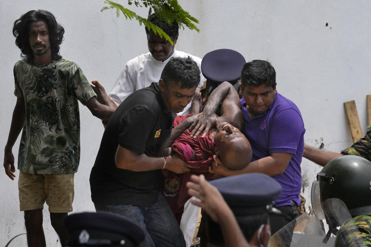 An injured Sri Lankan Buddhist monk is being carried away who among many other anti-government protesters were injured after attacked by government supporters outside prime minister Mahinda Rajapaksa's residence in Colombo, Sri Lanka, Monday, May 9, 2022. Government supporters on Monday attacked protesters who have been camped outside the offices of Sri Lanka's president and prime minster, as trade unions began a “Week of Protests” demanding the government change and its president to step down over the country’s worst economic crisis in memory. (AP Photo/Eranga Jayawardena)