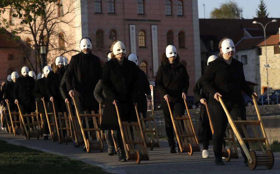 In this picture taken on Thursday, April 18, 2019, participants dressed in black, wearing masks, beating drums and pushing small carts that make a synchronized and loud sound take part in an Easter procession through the streets of Ceske Budejovice, Czech Republic. (AP Photo/Petr David Josek)