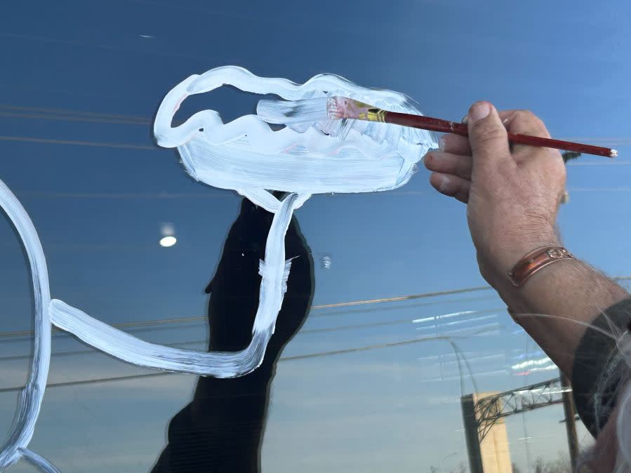 Gary Locklier paints the windows in front of Cafe 290 in Manor. (KXAN: Frank Martinez)