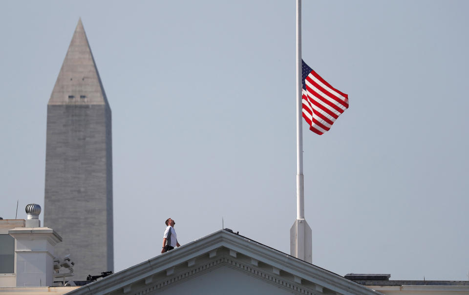 A worker looks up after lowering the flag over the White House in Washington to half-staff to honor victims of the shooting at the Capital Gazette Newspaper. (Photo: Kevin Lamarque / Reuters)