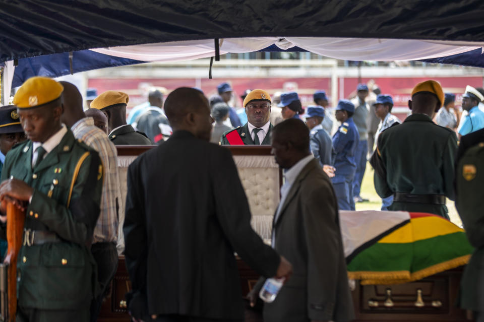 A member of the presidential guard stands to attention as members of the public view the body of former president Robert Mugabe as it lies in state at the Rufaro stadium in the capital Harare, Zimbabwe Friday, Sept. 13, 2019. The ongoing uncertainty of the burial of Mugabe, who died last week in Singapore at the age of 95, has eclipsed the elaborate plans for Zimbabweans to pay their respects to the former guerrilla leader at several historic sites. (AP Photo/Ben Curtis)